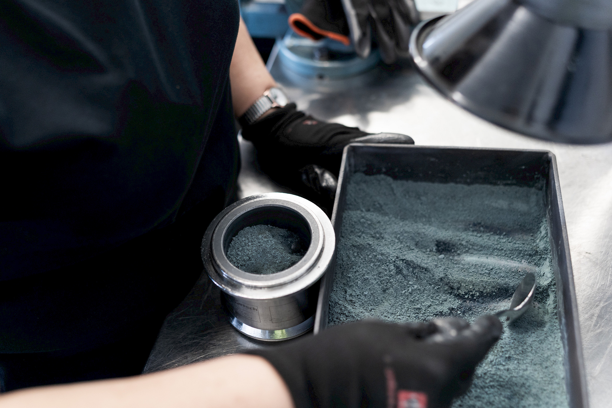 Person schaufelt Pulver in rechteckiger Form im Labor.