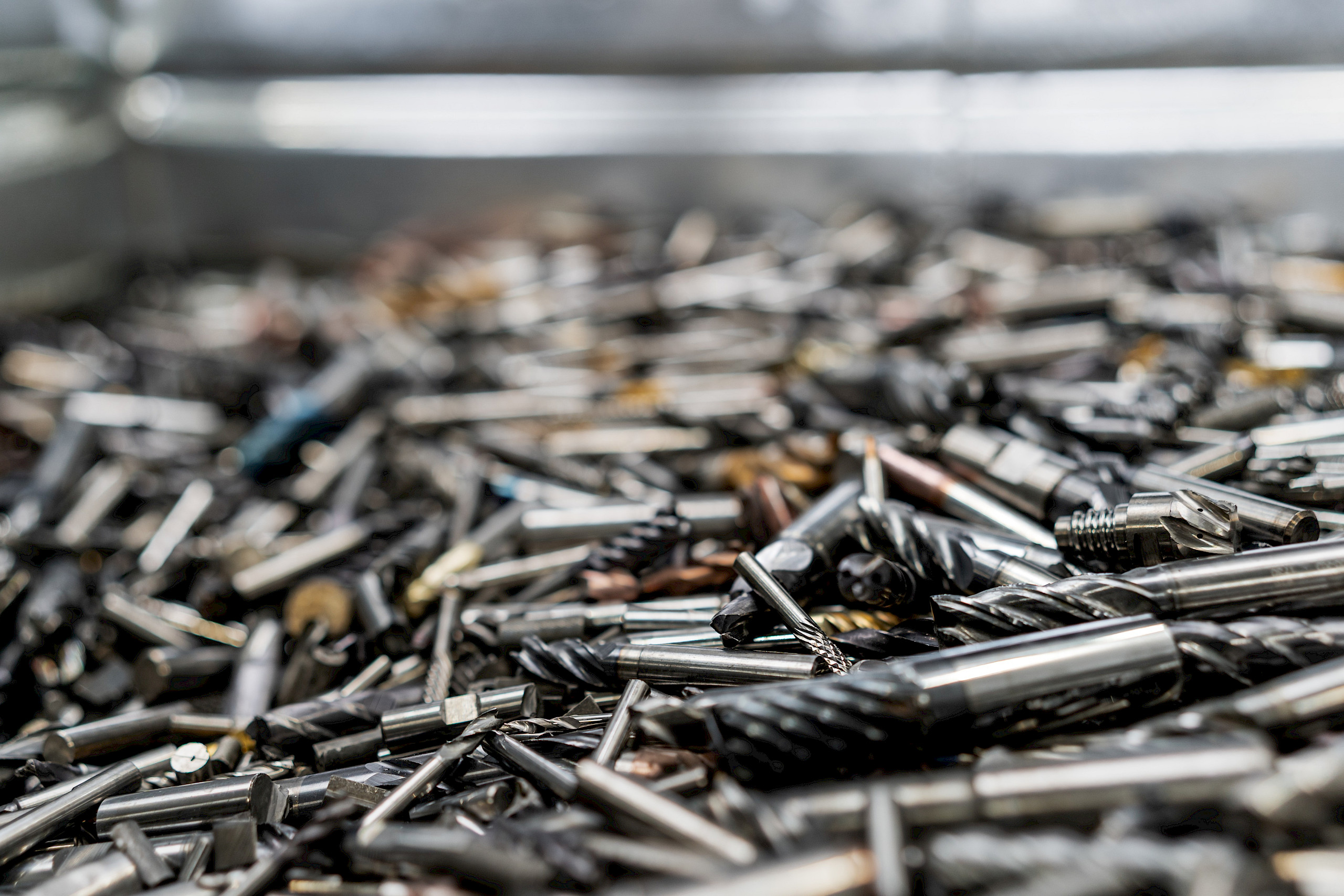 Ein Haufen unterschiedlicher Metallwerkzeuge, darunter Schneid- und Bohrwerkzeuge, auf einem Haufen gestapelt.