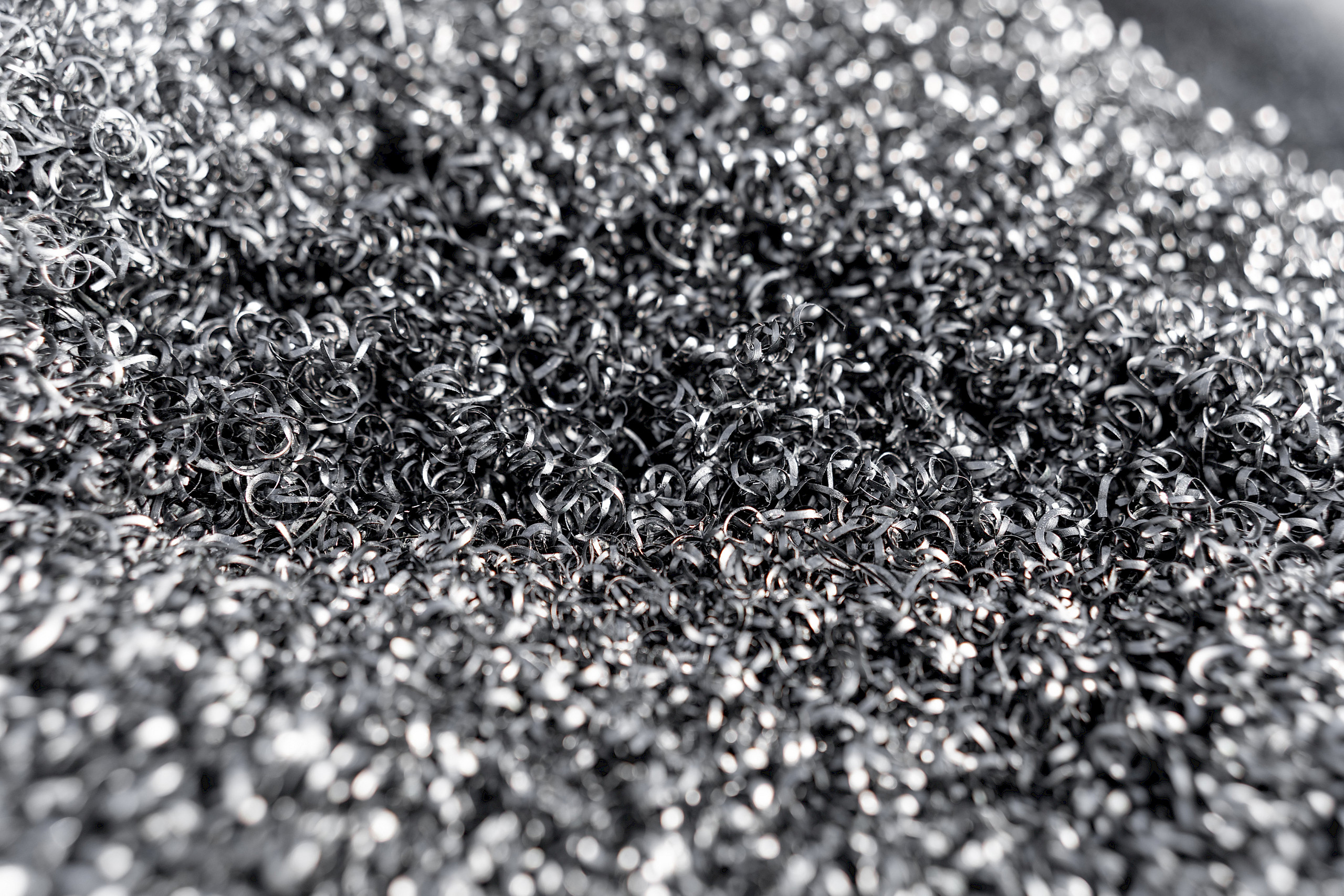Eine Nahaufnahme von metallischen Spänen. Sie sind klein, silbrig und in unregelmäßigen Spiralen geformt.