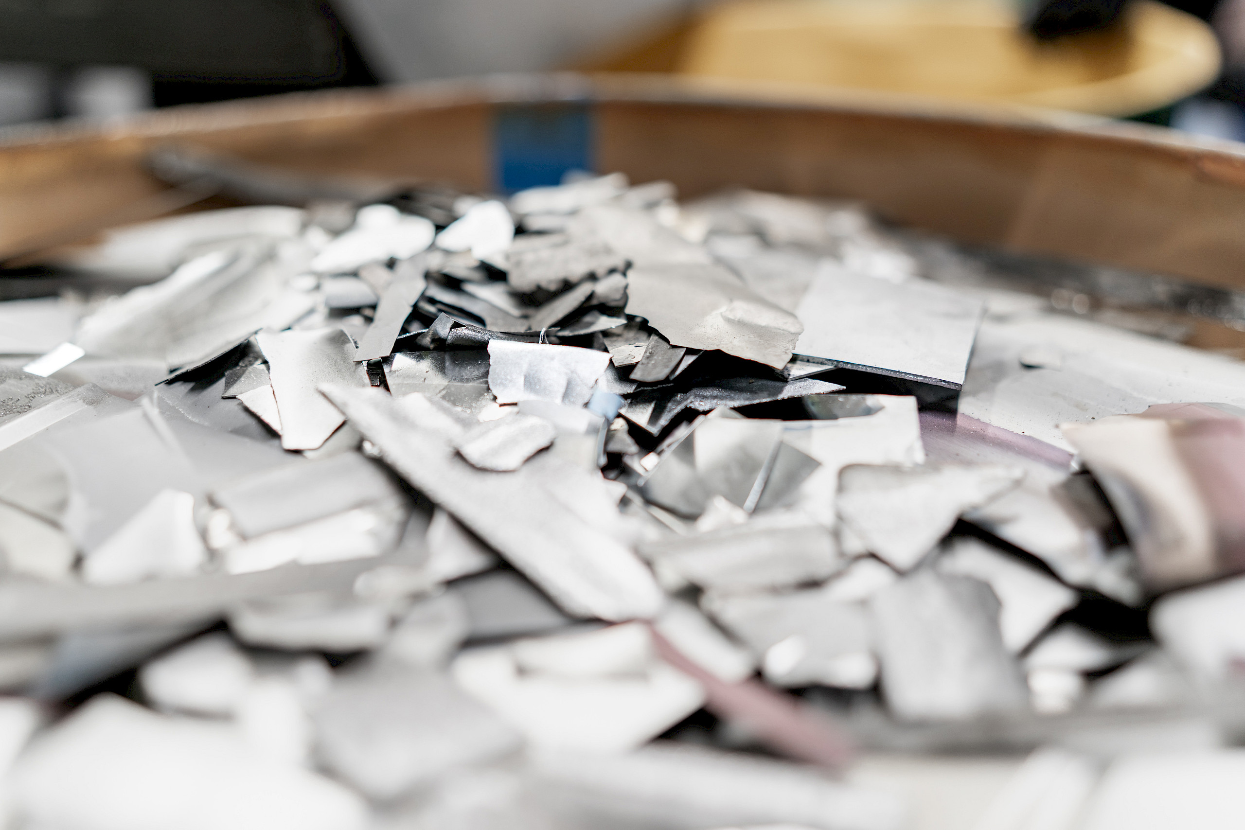 Ein Haufen aus kleinen, unregelmäßigen Metallstücken, wahrscheinlich Titanlegierungen, auf einer Metalloberfläche.