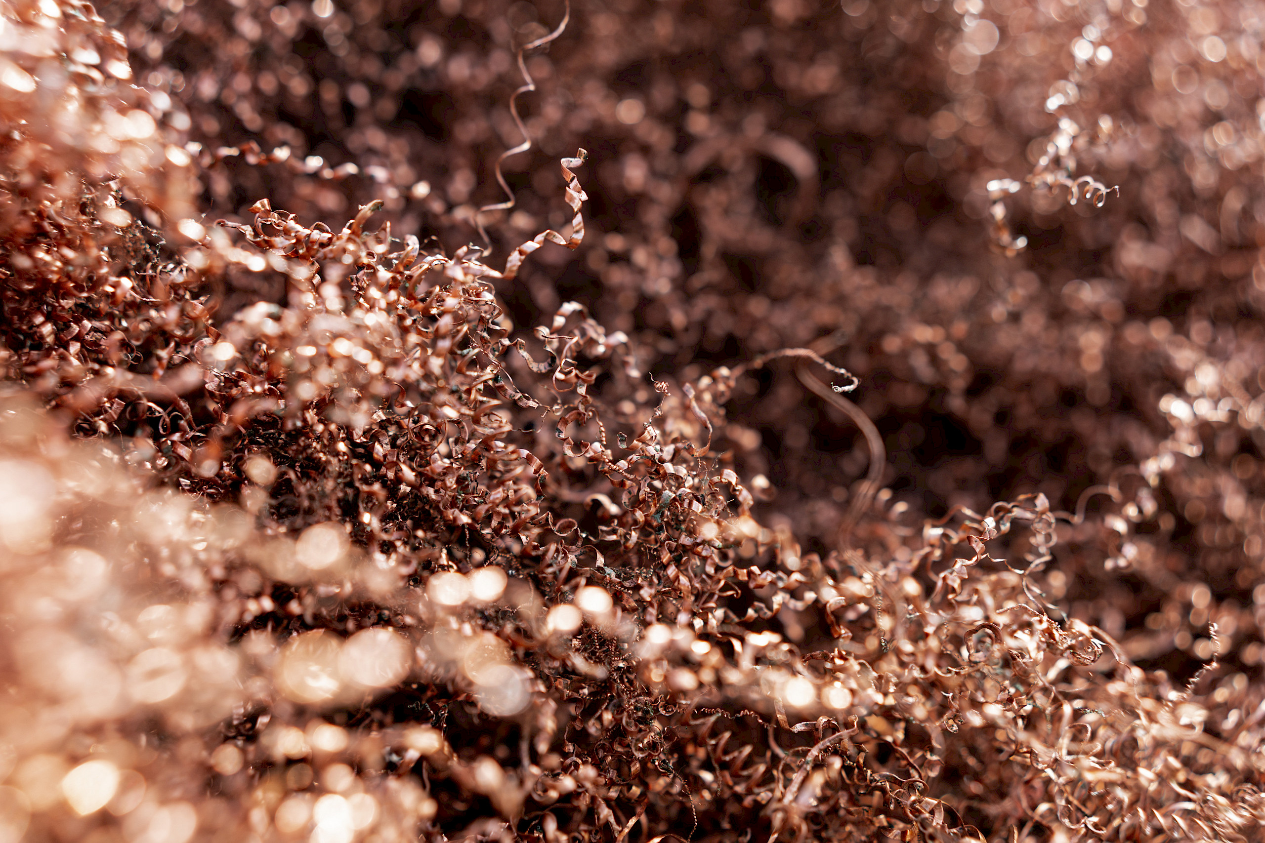 Nahaufnahme von wirren, bronze- oder kupferfarbenen Spänen, die ungleichmäßig verteilt sind und im Licht schimmern.